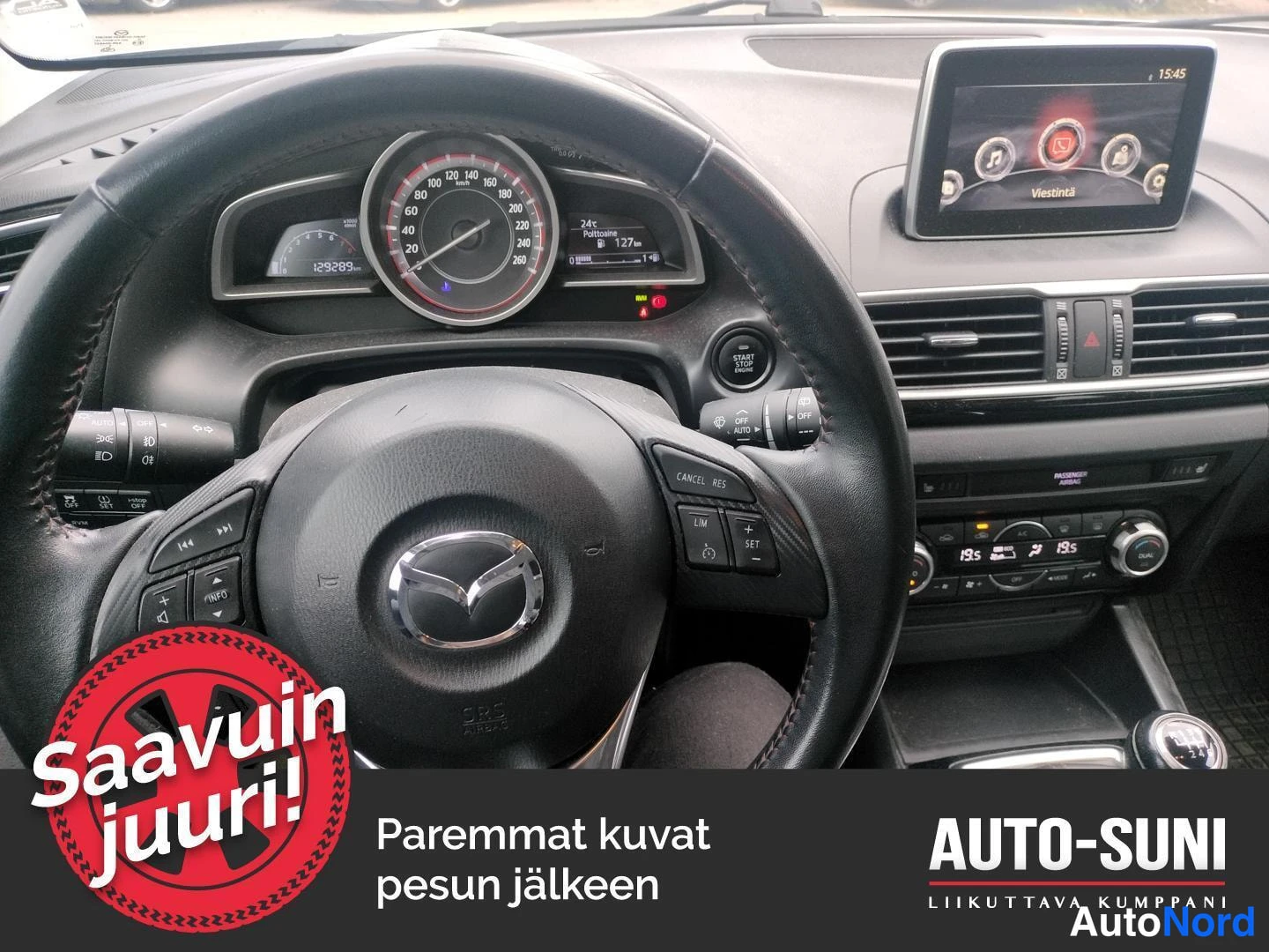 Muu: Mazda3:n kojelauta: mittaristo näyttää 129283 km, keskinäinen näyttö ja ilmastointipaneeli näkyvissä.