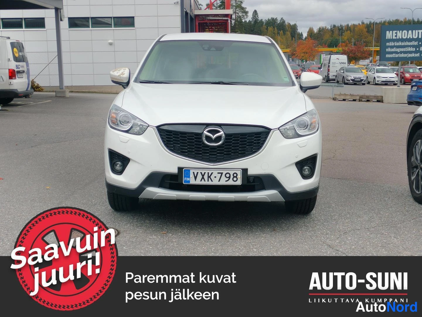 Edestä: Valkoisen Mazda CX-5 -henkilöauton etupää suoraan edestä kuvattuna, rekisteritunnus.