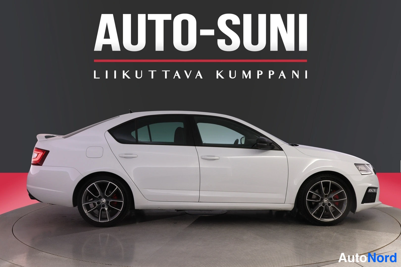 Takaviisto: Valkoinen Škoda Octavia -sedan sivunäkymä vasemmalta, tummat kevytmetallivanteet, takavalo ja etuosa nätisti esillä studio-taustaa vasten.