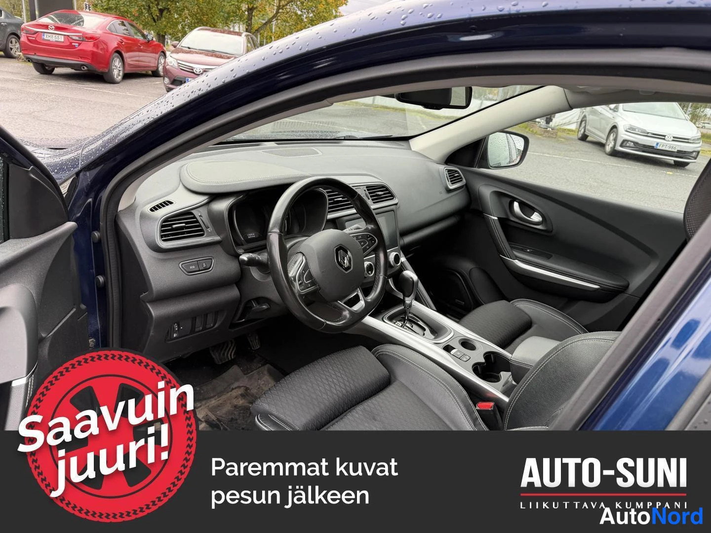 Muu: Auto-Suni-logolla varustettu kuva auton ohjaamosta, jossa näkyvät ohjauspyörä, kojelauta ja etuistuimet.