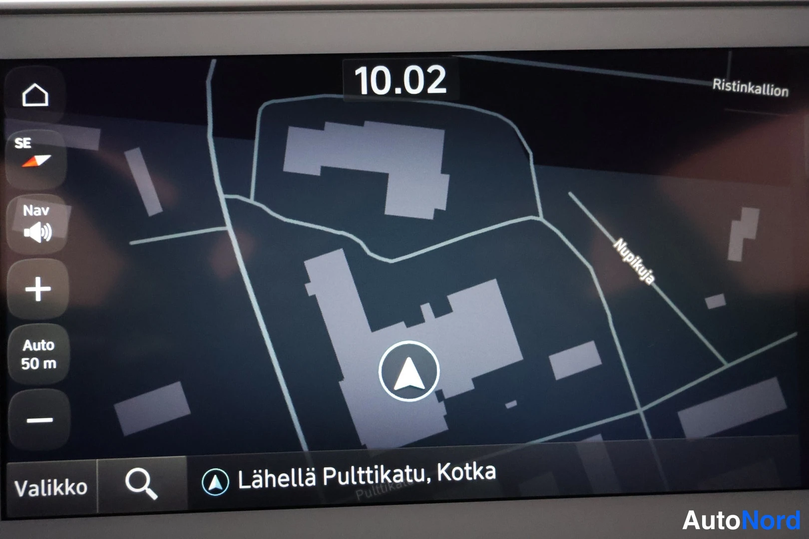 Muu: Auton infotainment-näytön navigointikartta, teksti 'Lähellä Pulttikatu, Kotka', kello 10.02 ja katuja kuten Nupukuja ja Ristinkallion.