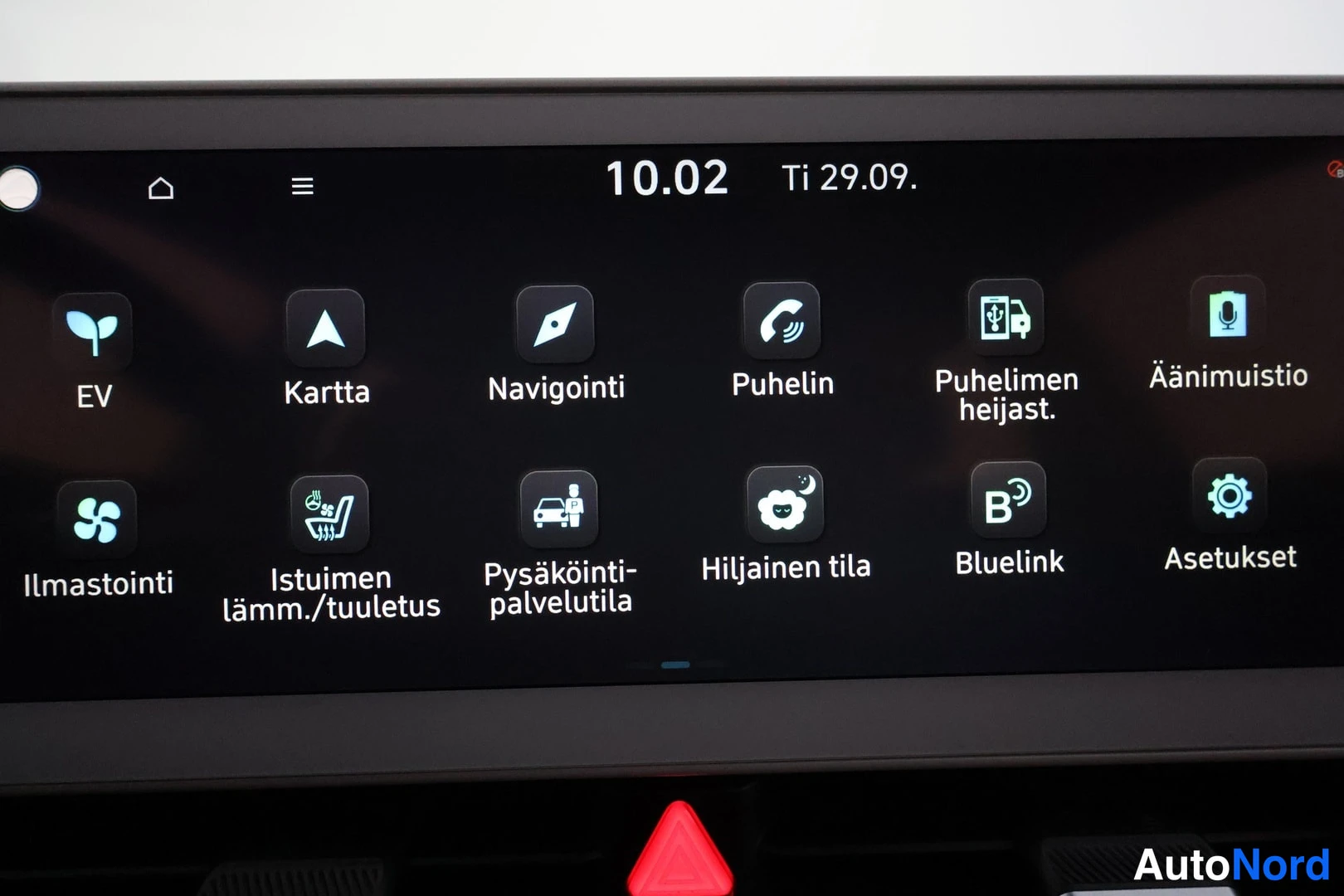 Yksityiskohta: Auton kosketusnäytön valikko, jossa on kuvakkeet muun muassa EV, Kartta, Navigointi, Puhelin, Ilmastointi ja Blueline-asetukset.