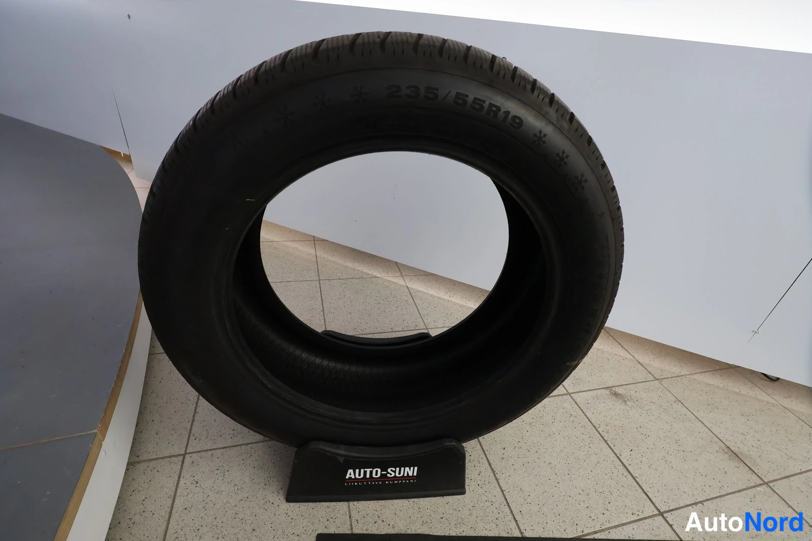 Yksityiskohta: Talousrengas seisoo jalustalla, kyljessä merkintä 235/55R19.