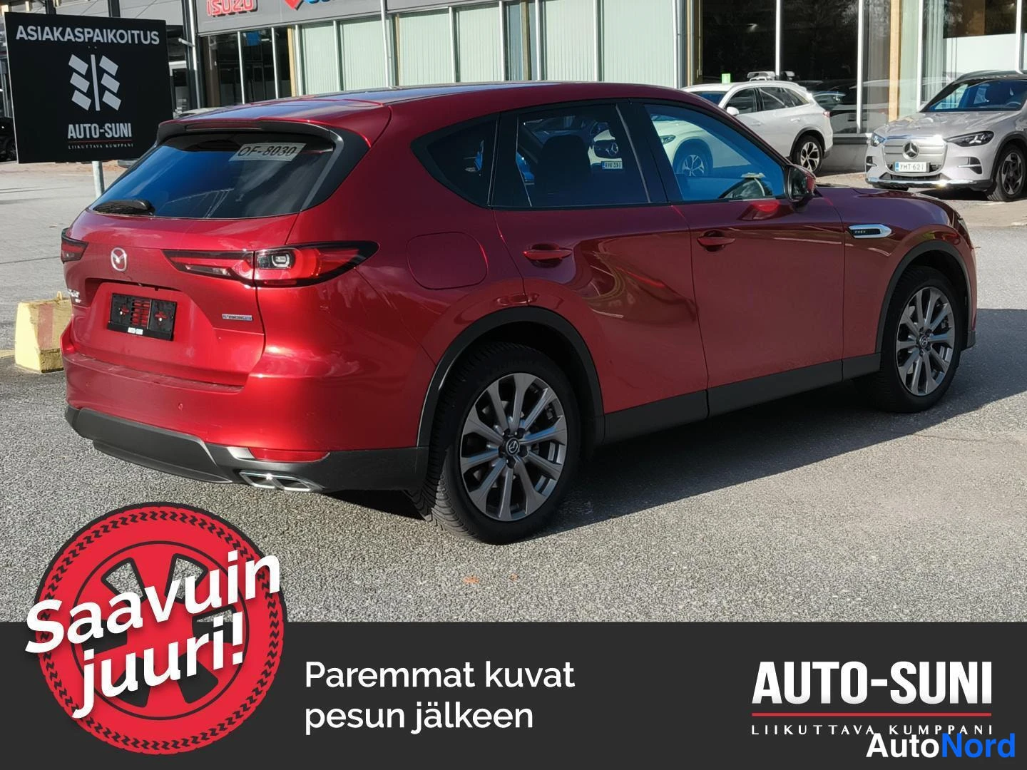 Takaviisto: Punainen Mazda CX-60 takaviistosta vasemmalta kuvattuna, takavalot ja pakoputket näkyvissä liikekeskuksen edustalla.