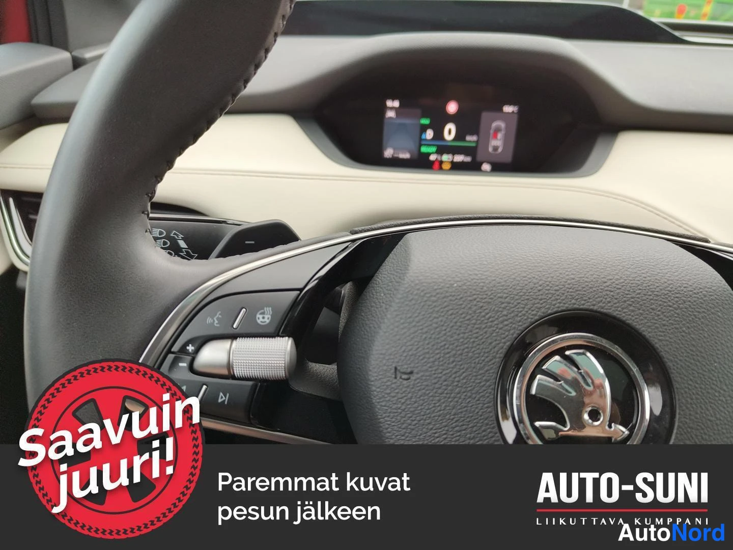 Ohjaamo: Lähikuva auton sisätiloista: Škoda-merkkinen ohjauspyörä ja sen takana digitaalinen mittarinäyttö.