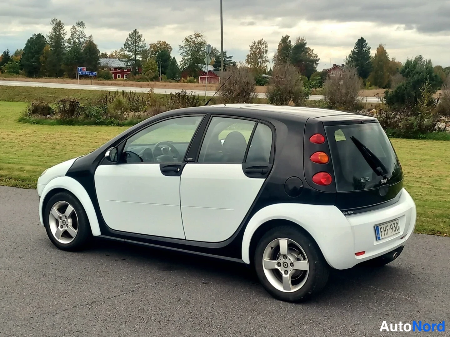 Takaviisto: Valkoinen ja musta Smart Forfour sivulta takaa kuvattuna, musta katto ja takapää, hopeiset vanteet.