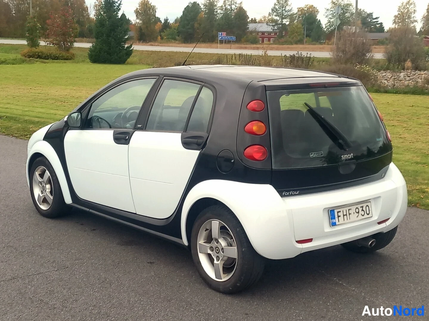 Takaviisto: Valkoinen ja musta Smart Forfour -henkilöauto takaviistosta oikealta kuvattuna, rekisterikilpi.