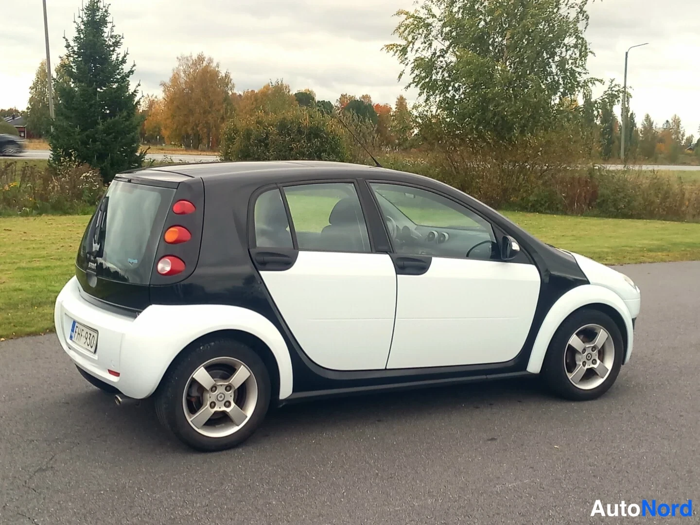 Takaviisto: Smart Forfour -auton takakolmasosanäkymä: musta katto ja takapää, valkoinen korirakenne, viisi oviaukkoa ja hopeiset vanteet.