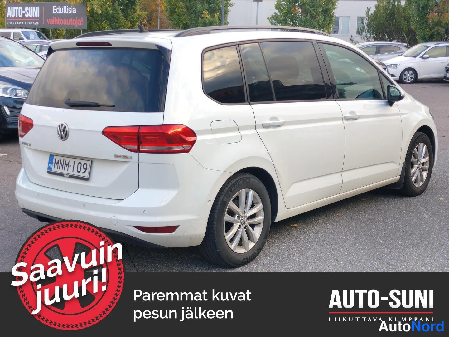 Takaviisto: Valkoinen Volkswagen Touran taka­kulmasta vasemmalta, rekisteritunnus, pysäköintialueella.