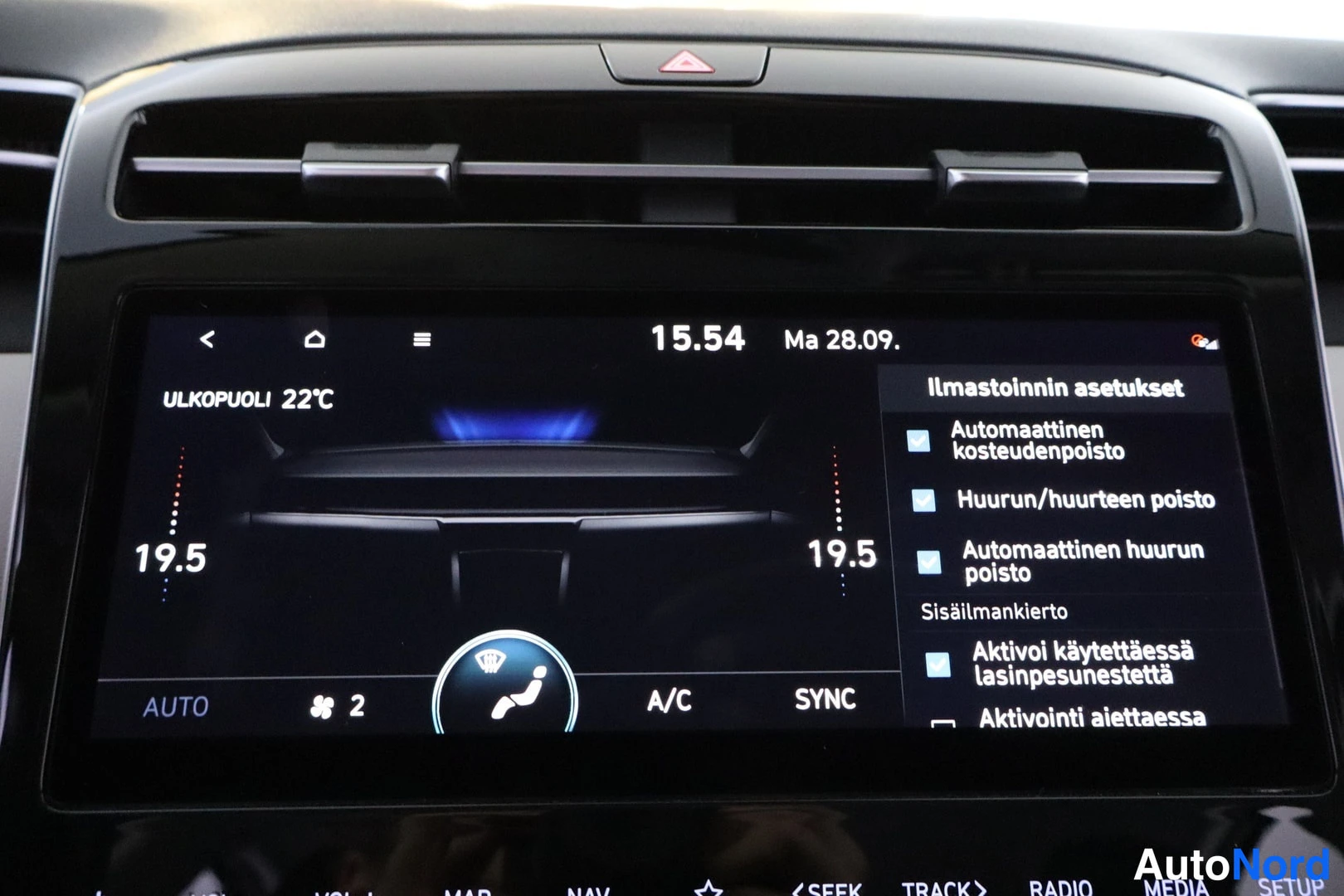 Muu: Kojelaudan infotainmentnäyttö näyttää ilmastoinnin asetuksia, ulkolämpötilaa 22 °C ja kaksivyöhykelämmitystä 19,5 asteessa.