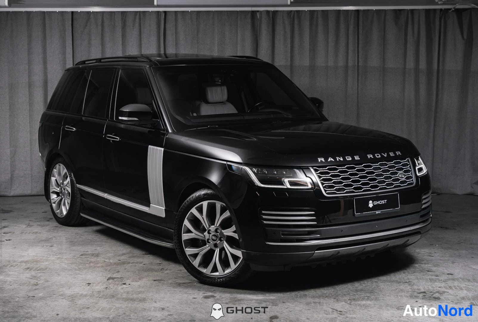 Etuviisto, nokka oikealle: Musta Land Rover Range Rover -maasturi kuvattu kolmannelta edestä, kylki ja konepellillä olevat RANGE ROVER -merkit sekä etusäleikkö näkyvät sisätiloissa