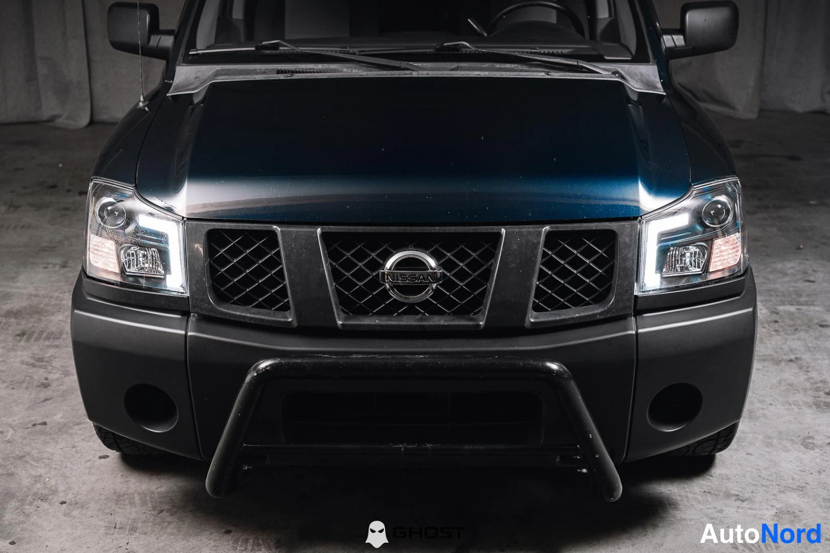 Edestä: Lähikuva Nissan Titanin etuosasta: musta säleikkö Nissan-tunnuksella, LED-ajovalot ja musta kaaripuskuri.