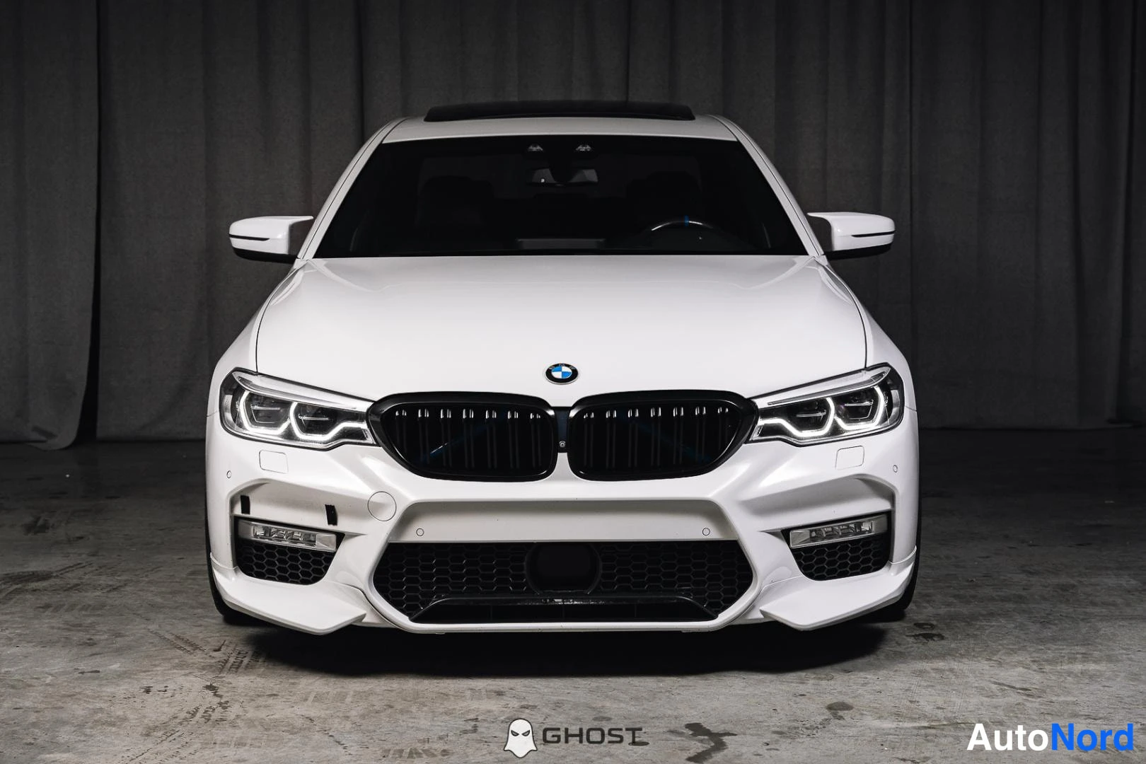 Edestä: Valkoinen BMW-sedan suoraan edestä, LED-ajovalot päällä ja musta etusäleikkö.