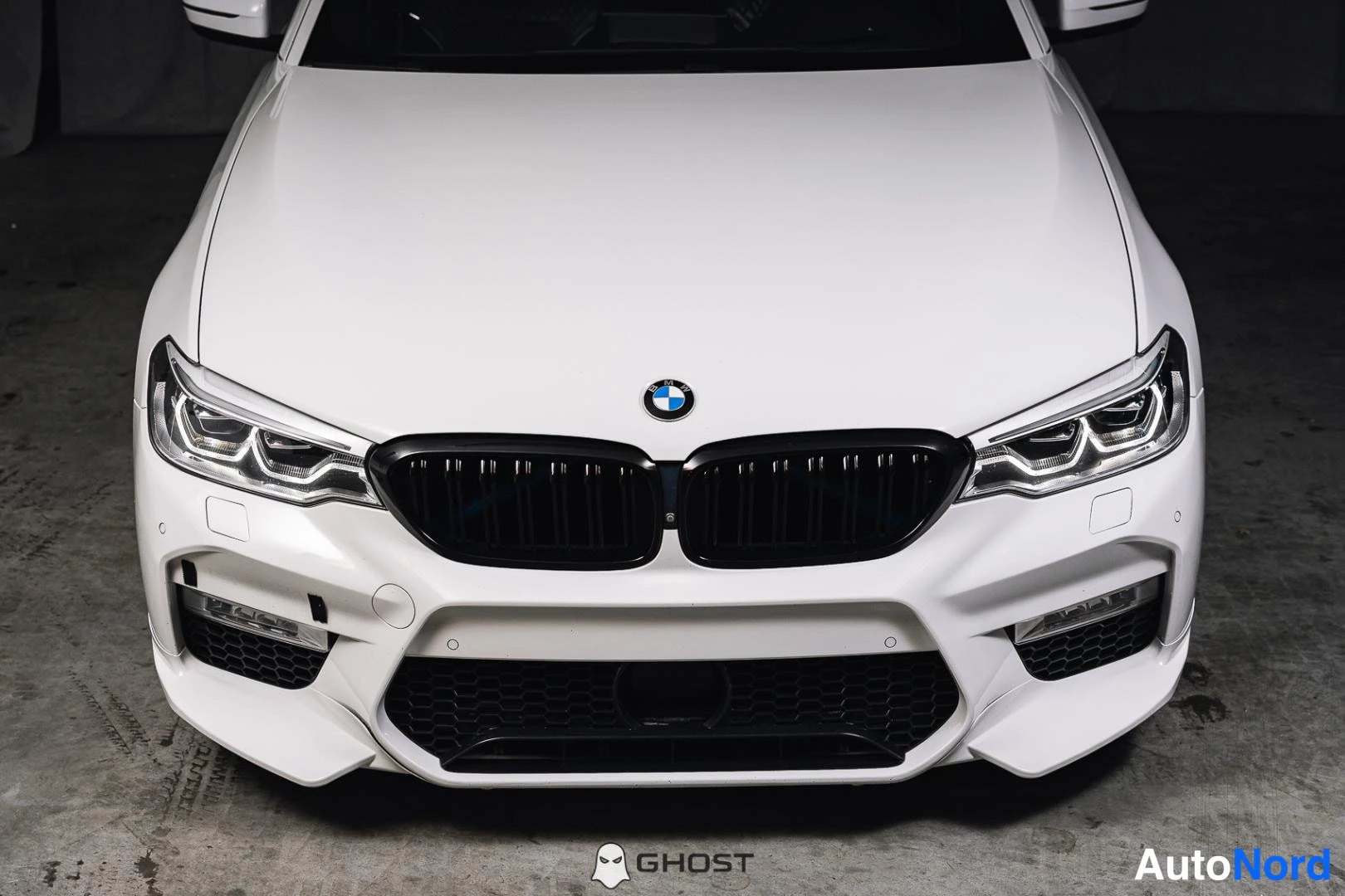 Edestä: Tarkkuuskuva valkoisen BMW:n etupäästä: musta munuaissäleikkö, BMW-tunnus ja sumuvalot.