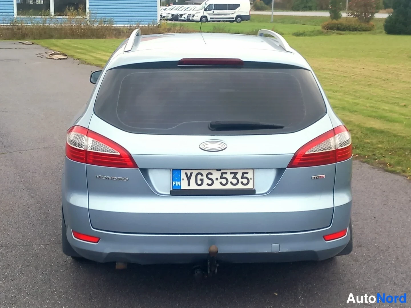 Takaa: Ford Mondeo -farmarin suora takanäkymä. Rekisterikilpi, kattokaiteet ja takaovissa kiinnitetty vetokoukun kaula näkyvät.
