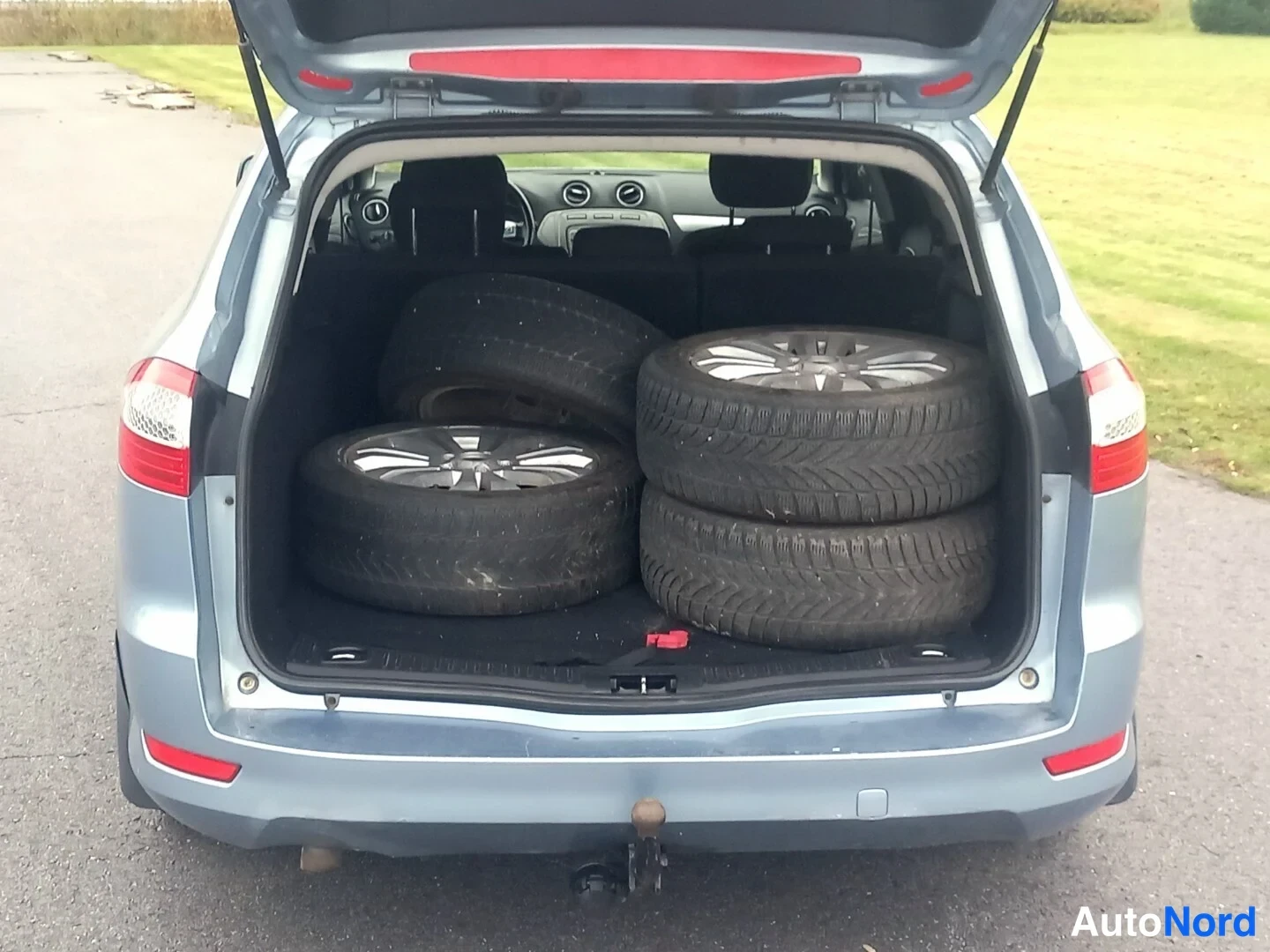 Takaa: Auto takaa avattu tavaratila: neljä talvirengasta vankkurissa, vetokoukku takapuskurissa.