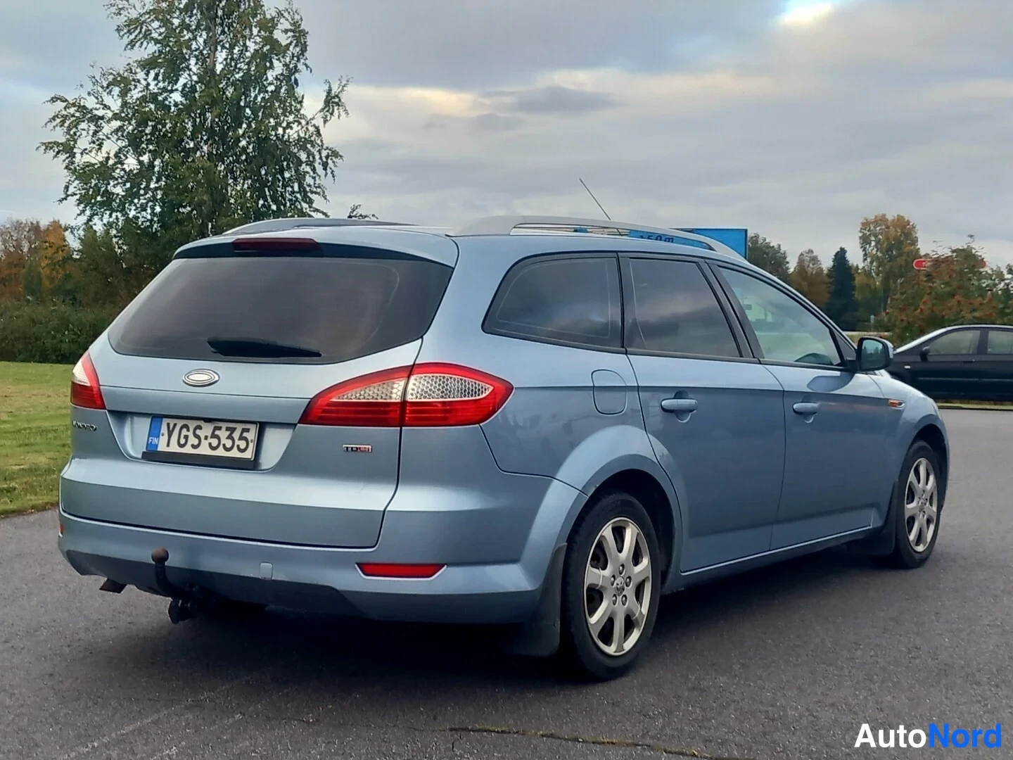 Takaviisto: Vaaleansininen Ford Mondeo -farmari kuvattuna takaa ja sivulta; rekisterikilpi, takavalot ja peräluukku näkyvät, sivuilta ovet ja kattokaiteet.