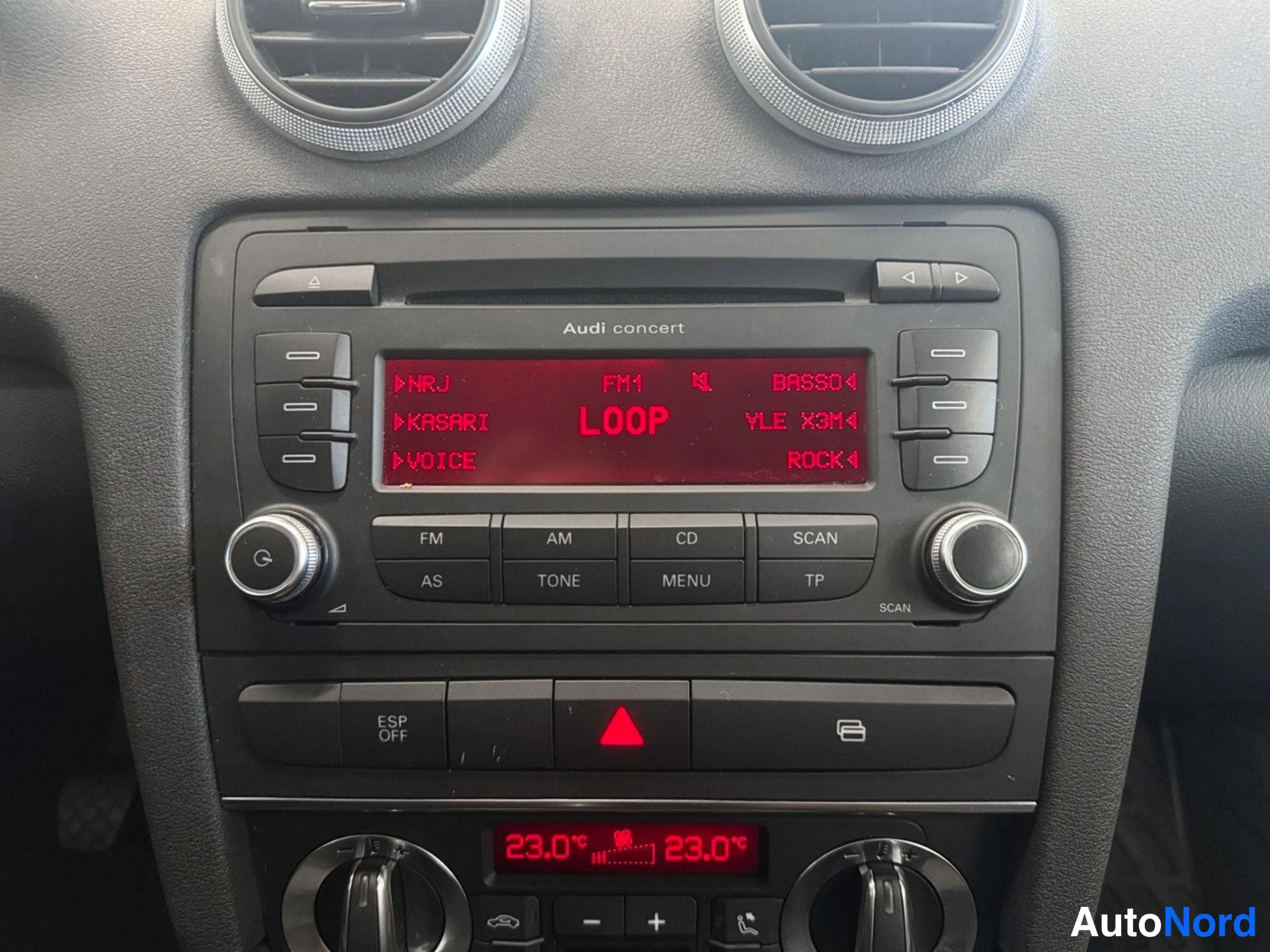 Sivulta: Audi concert -radioyksikkö auton kojelaudassa: punainen näyttö näyttää FM1-kanavan ja LOOP-tekstin, painikkeita FM, AM, CD, SCAN, TONE, MENU, TP; alapuolella ES