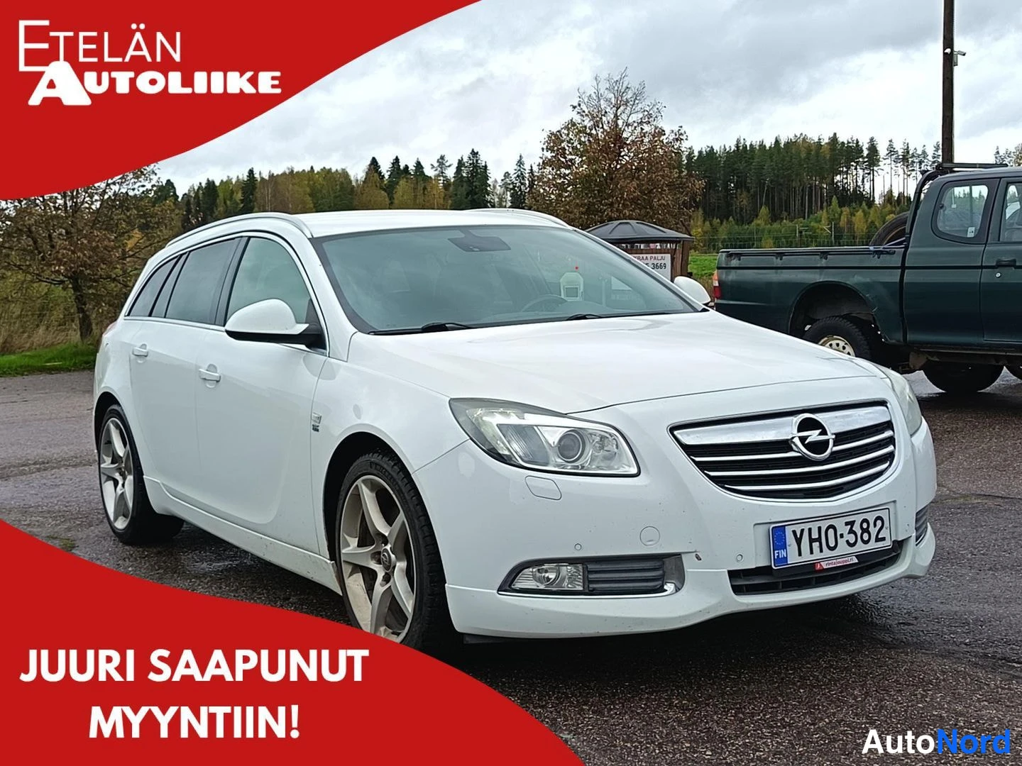 Etuviisto, nokka oikealle: Valkoinen farmariauto kolmisivukulmassa, rekisterikilpi.