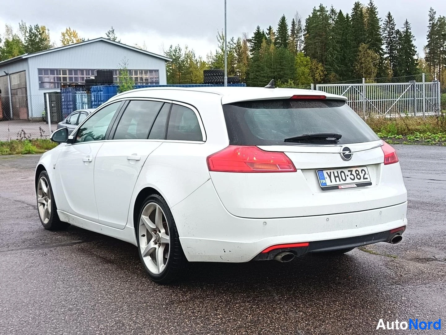Takaviisto: Valkoinen farmariauto takaviistosta, rekisterikilpi.