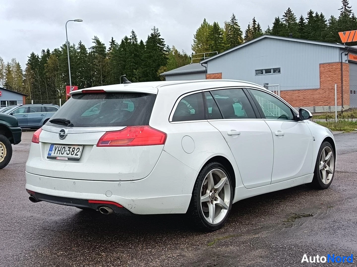 Takaviisto: Valkoinen farmariauto takaviistosta oikealta, rekisterikilpi.