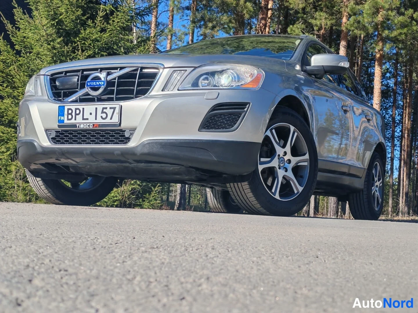 Etuviisto, nokka vasemmalle: Volvo XC60:n keula edestä vasemmalta kuvattuna, etumoottoritilan ritilä ja Volvo-merkki, rekisterikilpi.