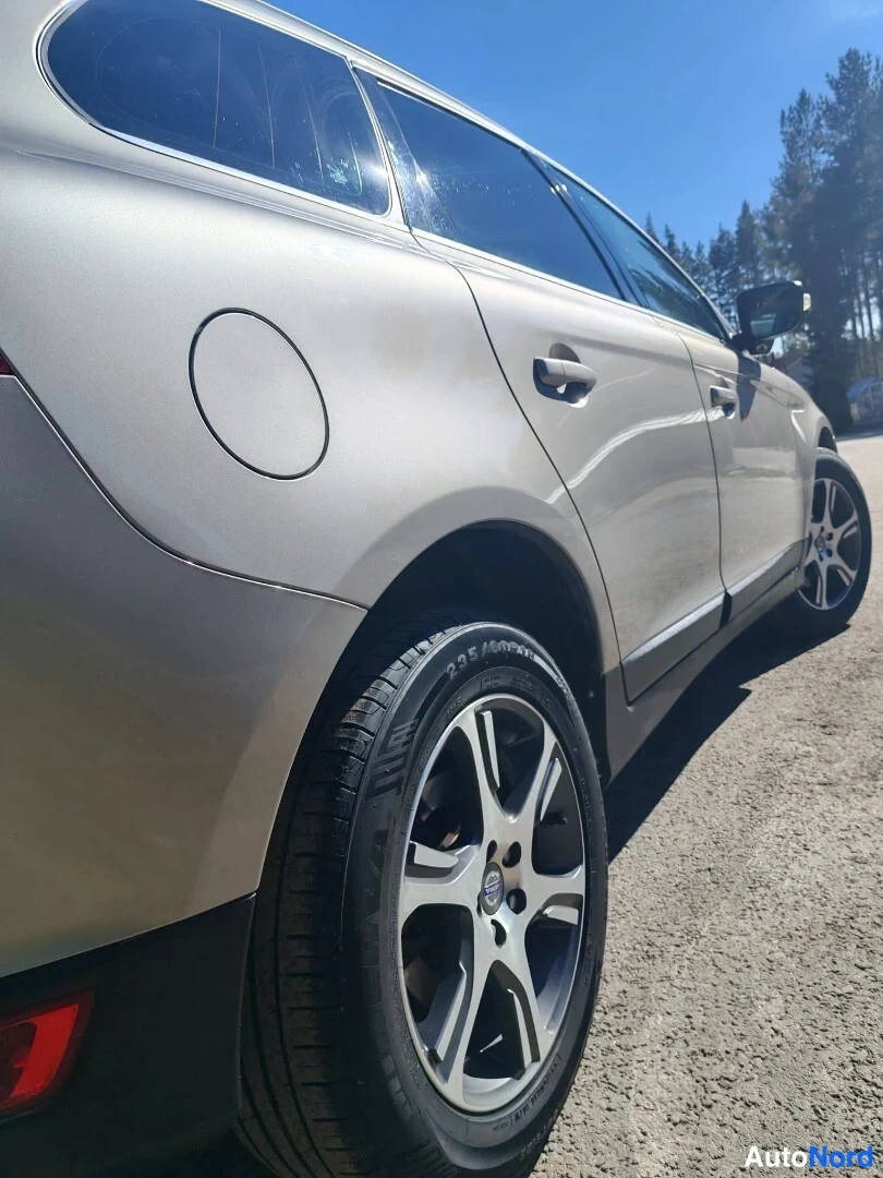 Sivulta: Volvo XC60:n takaosa sivulta, vaalean beige metalliväri, viisitoistavartinen kevytmetallivanne ja polttoainesuukansi näkyvissä.