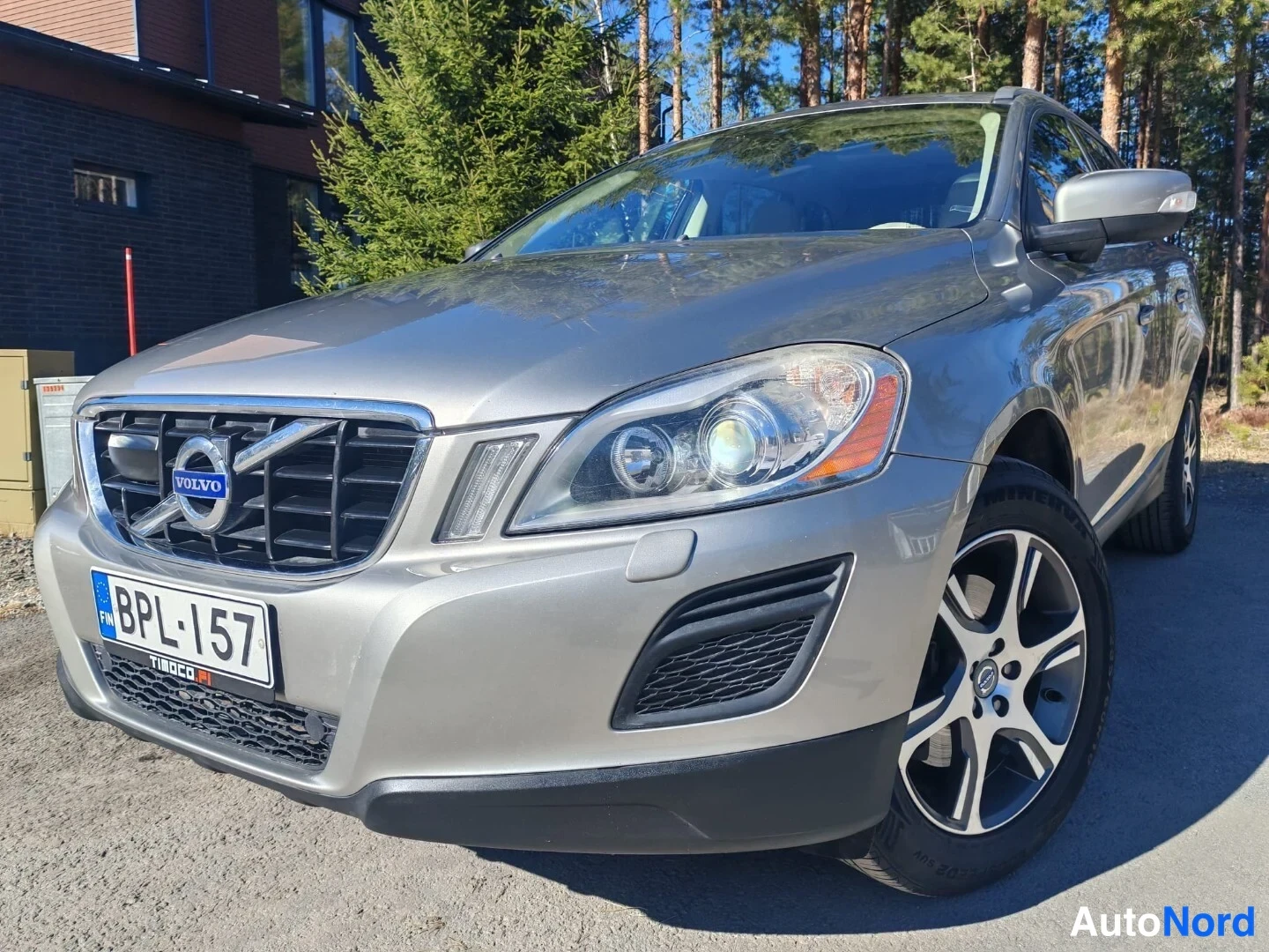 Etuviisto, nokka vasemmalle: Kulmakuva hopeanvärisen Volvo XC60:n etupäästä vasemmalta: Volvo-merkkinen etusäleikkö, ajovalot, sumuvaloaukot ja rekisterikilpi näkyvät.
