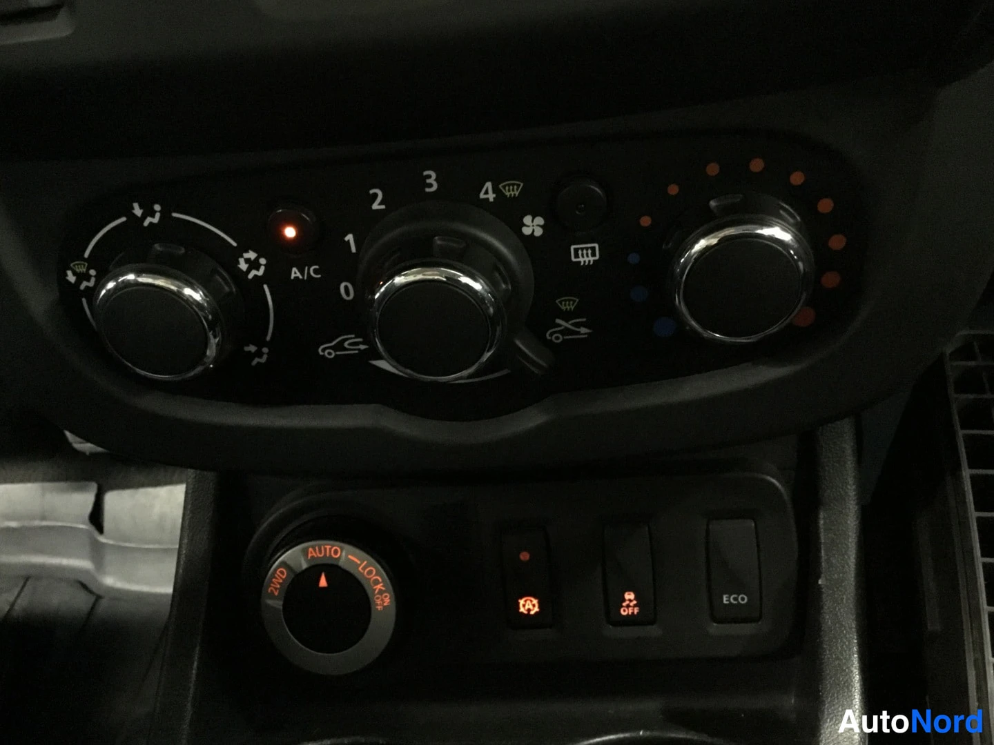 Yksityiskohta: Kojelautailma (kliimauspanneeli) kolmella säätörullalla, tekstit '2ND AUTO –LOCK', 'A/C', 'ECO', serta EPS OFF- ja lukinnappit.