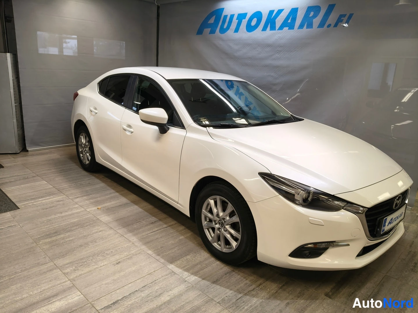Etuviisto, nokka oikealle: Mazda3 sedan etuviisto oikealta, valkoinen.