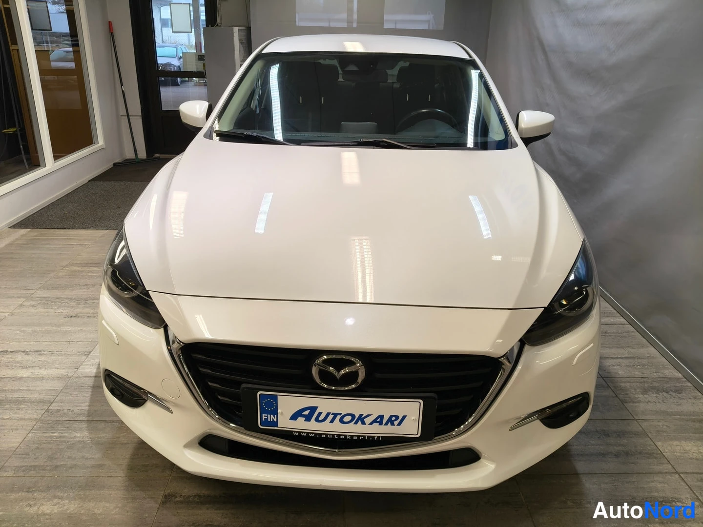 Edestä: Mazda3 sedan edessäpäin, valkoinen.