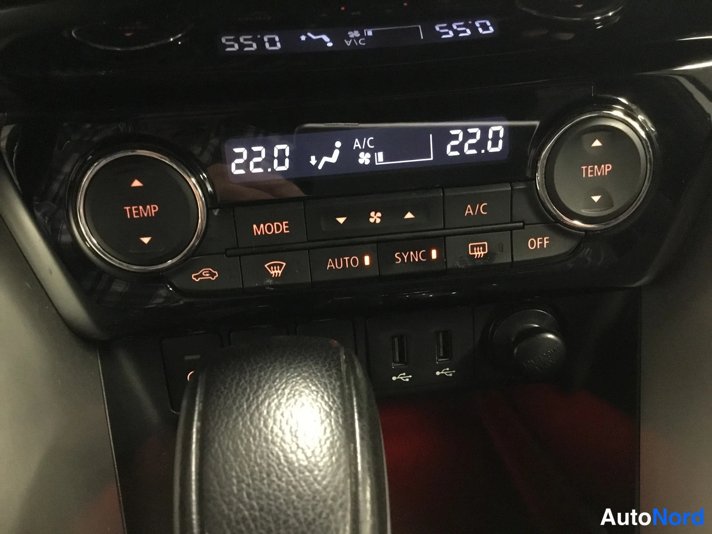 Muu: Auton kojelaudan automaattinen kaksivyöhykeilmastointi: näytössä lukee 22.0 ja A/C, ympärillä TEMP-ja MODE-painikkeet sekä USB-portit. Ohjauspaneeli on kiiltävä