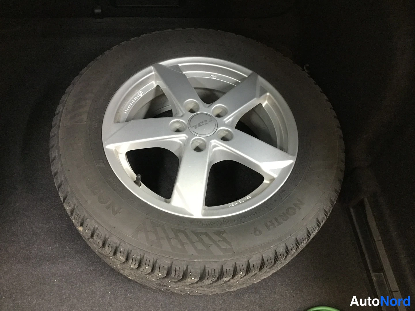 Muu: Yksityiskohta hopeavanteesta ja pikkukoloilla varustetusta nastarenkaasta, kyljessä teksti NORTH 9.
