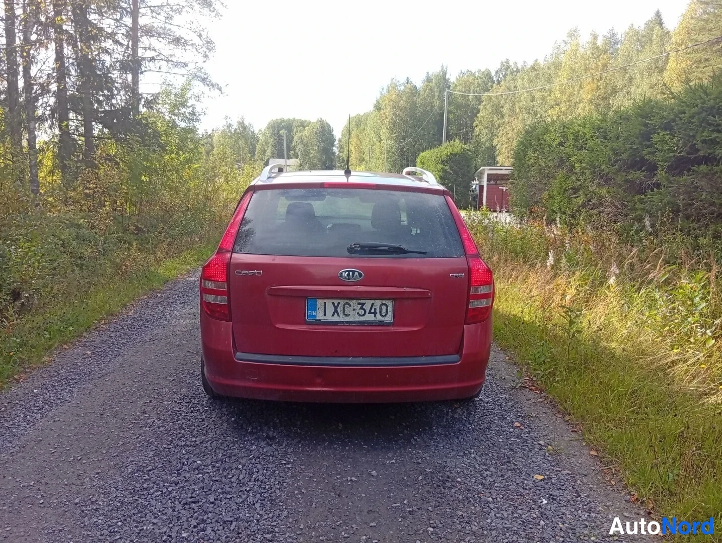 Takaa: Punaisen Kia Ceed -farmarin takanäkymä hiekkatiellä, cee'd- ja CRDi-tekstit sekä rekisteritunnus näkyvissä.