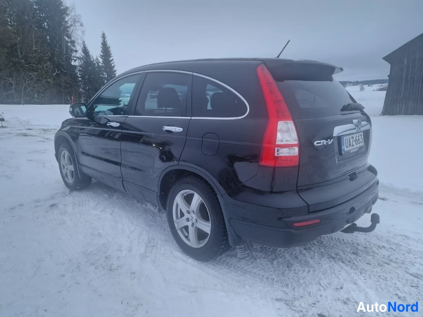 Takaviisto: Musta Honda CR-V takaa oikealta kolmanneltsektiolta lumessa; takana CR-V-merkintä ja rekisterikilpi.
