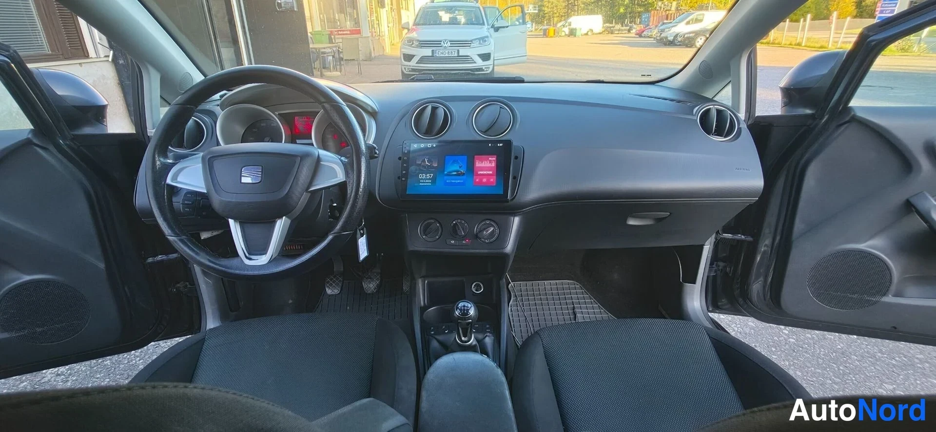Muu: Kuva ohjaamosta taaksepäin: Seat-ohjauspyörä, Android-näytöllinen radiopaneli ja viisi istumapaikkaa näkyvissä.