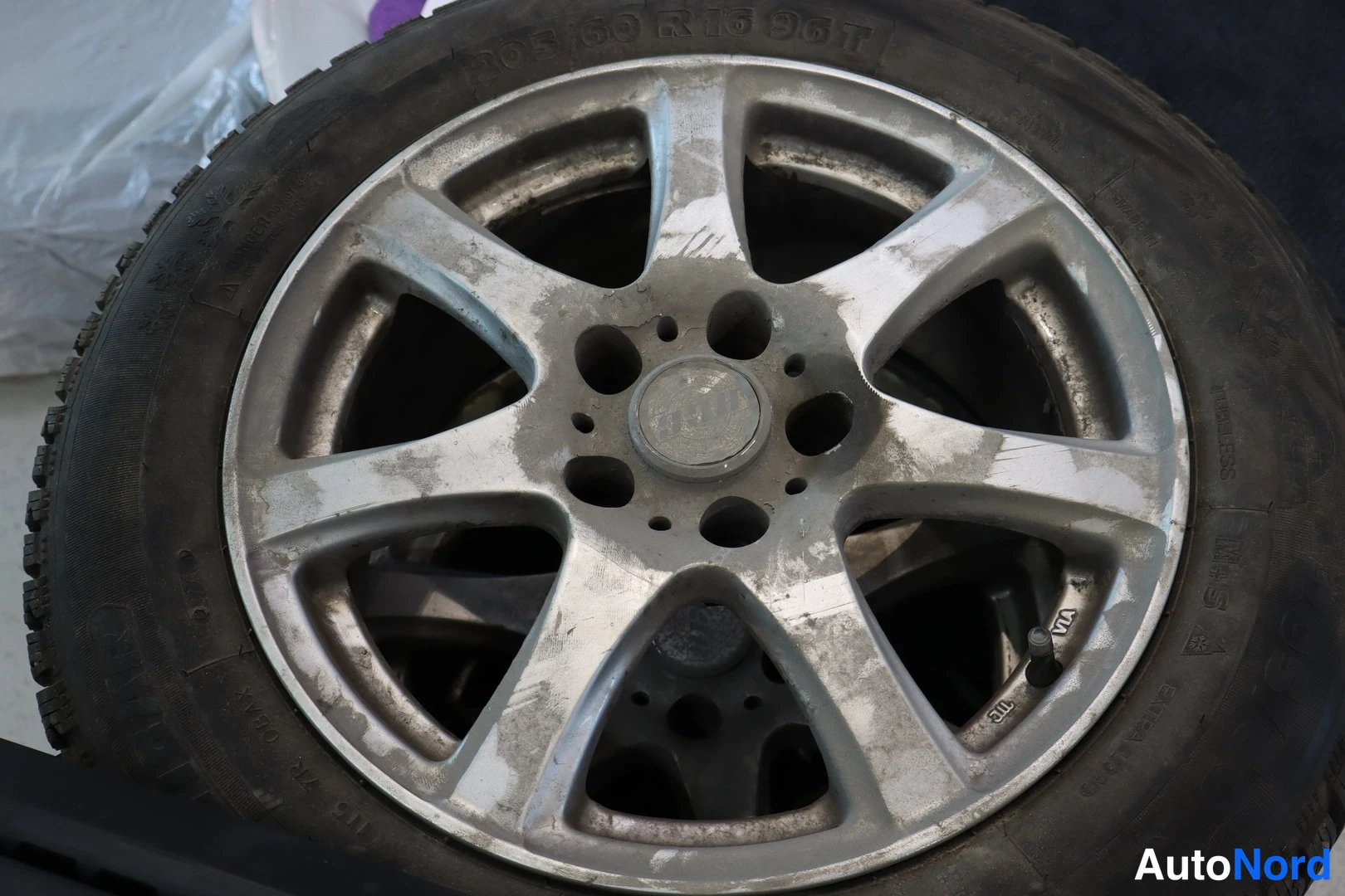 Yksityiskohta: Hopeanvärinen kevytmetallivanne lähikuvassa, renkaan sivussa lukee 205/60 R16 96T.