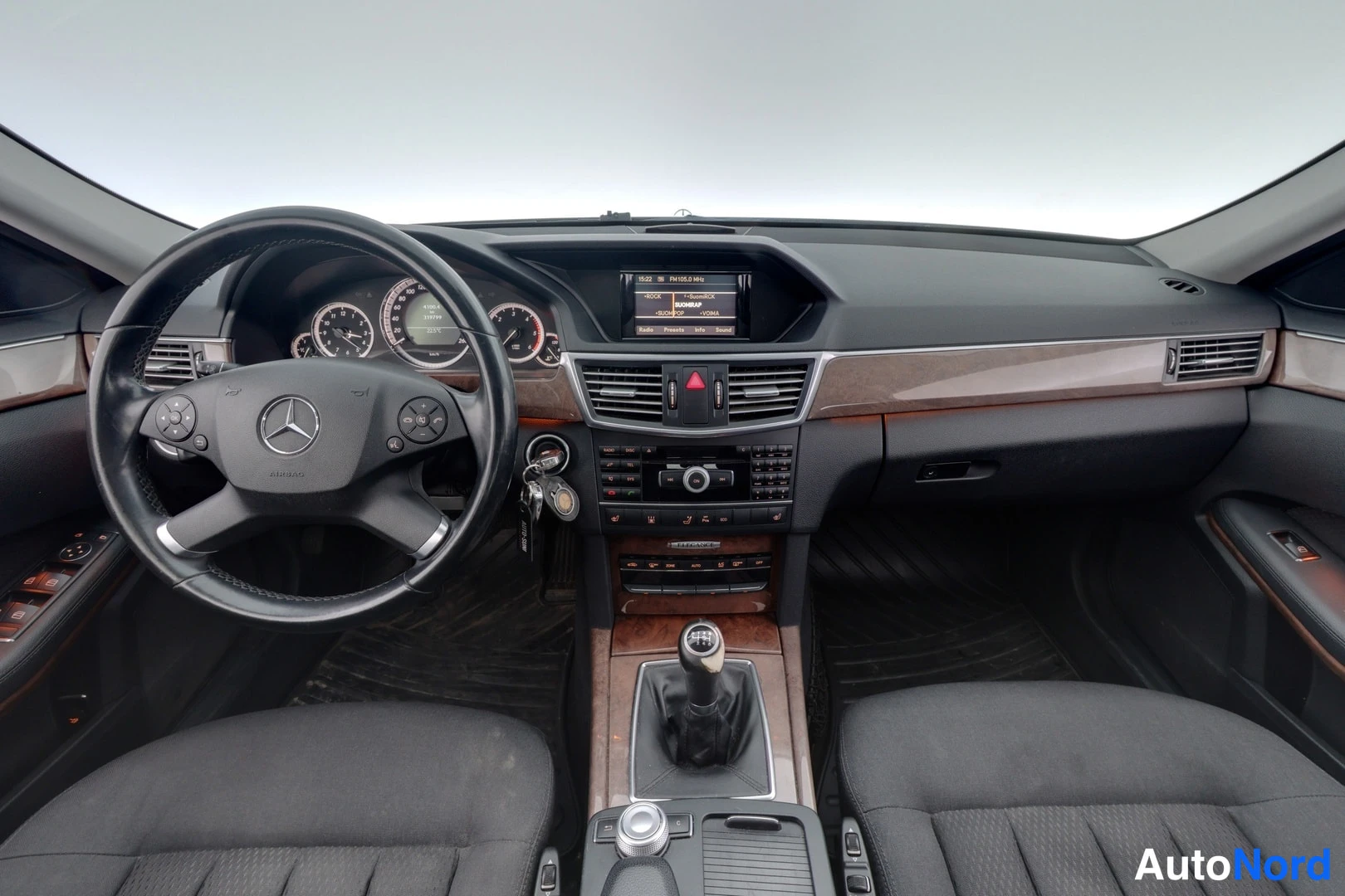 Muu: Mercedes-Benzin ohjaamo edestä: ratin Mercedes-tunnuksella, analogiset mittarit, keskinäytöllinen radio, manuaalivaihteiston vaihdevipu ja puiset koristeelistat