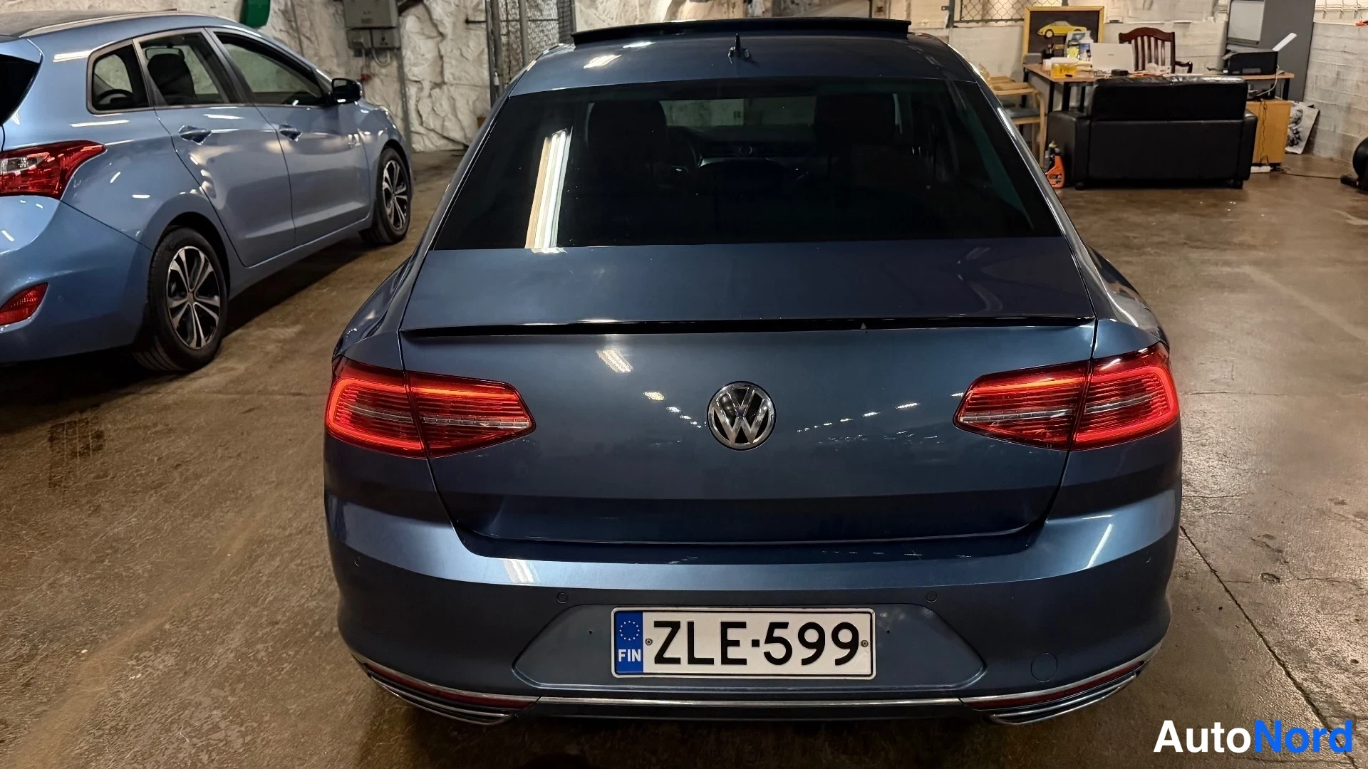 Takaa: Volkswagen-henkilöauton takaosa yläviistosta takaa: tummansininen koripelti, VW-merkki, punaiset takavalot, rekisteritunnus ja kattoon asennettu kattoluukku.