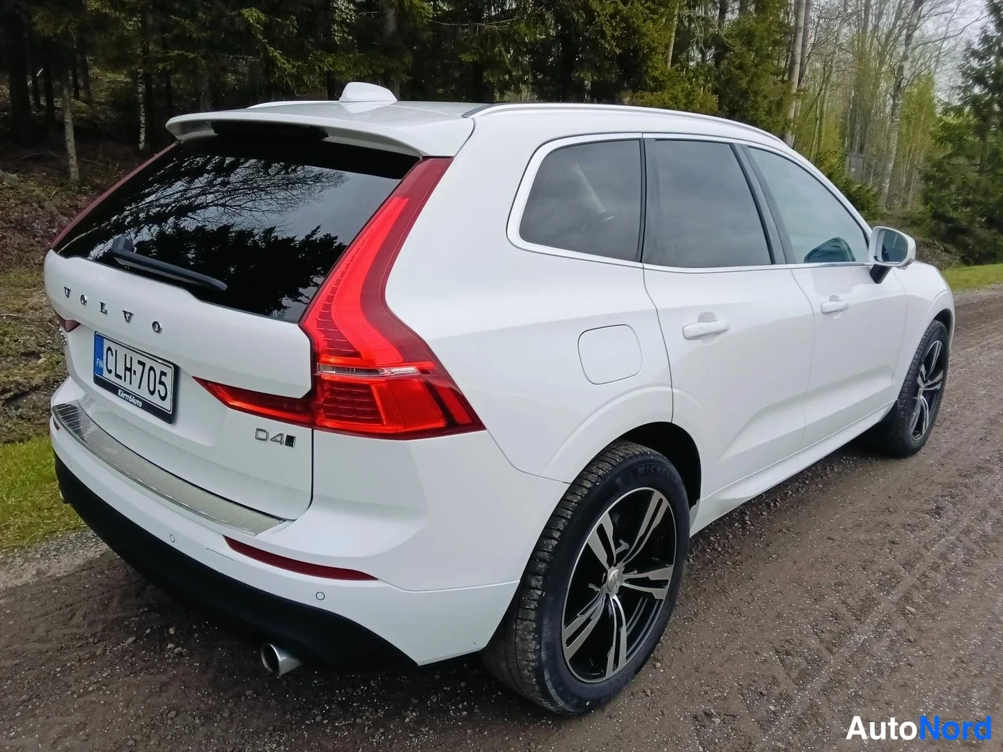 Takaviisto: Valkoinen Volvo XC60 takaviistosta vasemmalta, D4-tunnus ja rekisterikilpi näkyvät, tummat kevytmetallivanteet.