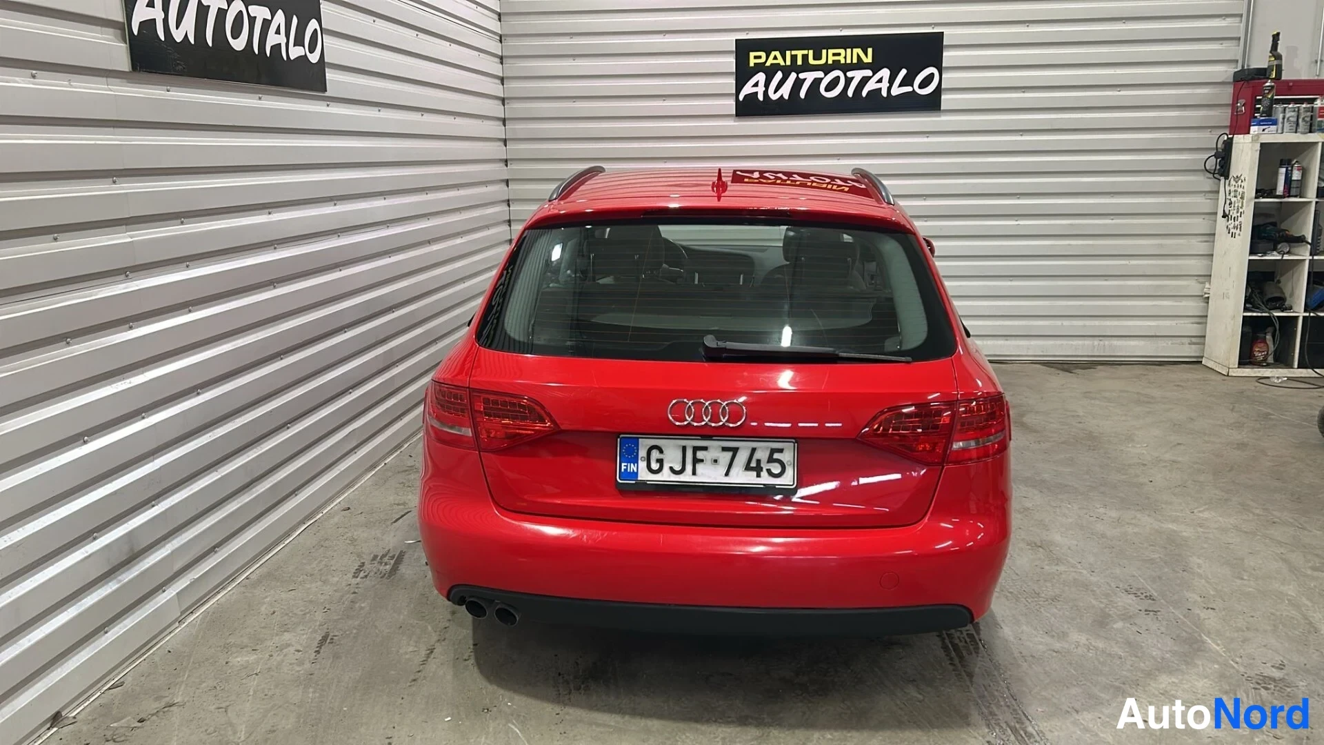 Takaa: Punaisen farmariauton takaosa suoraan takaa, rekisterikilpi ja Audi-merkki näkyvissä.