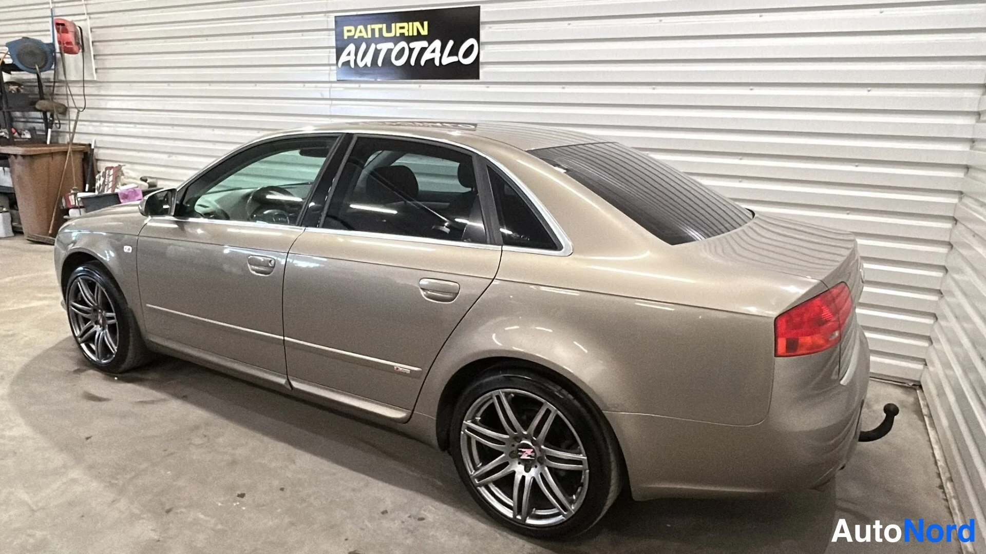 Takaviisto: Beige sedan takaviistolta kuvattuna; perä, takavalot ja kylki näkyvissä autotallissa.