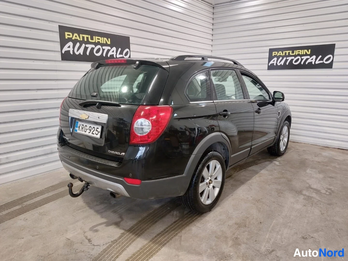 Takaviisto: Musta Chevrolet Captiva -katuauton taka- ja oikeanpuoleinen etusivu. Auto on pysäköity kellarin tasolle. Laitteisto näkyy takapäässä.