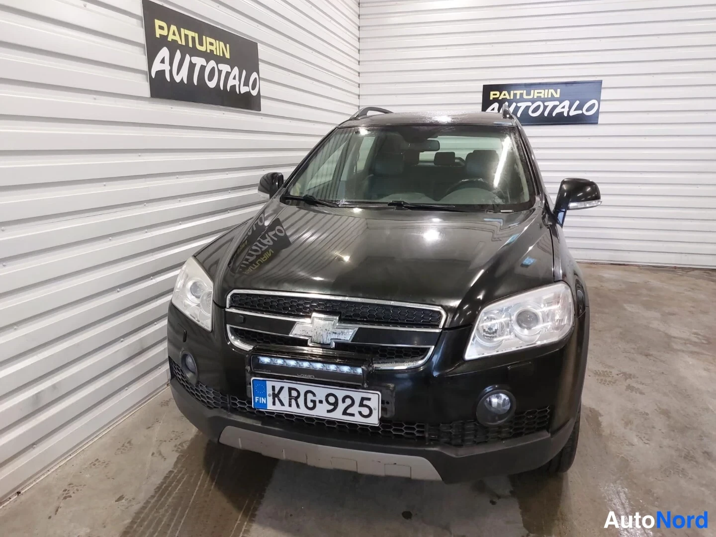 Edestä: Musta SUV etupäältä suoraan kuvattuna autotallissa, jäähdelauta, rekisterikilpi ja etupuskurin lisävalo näkyvät.