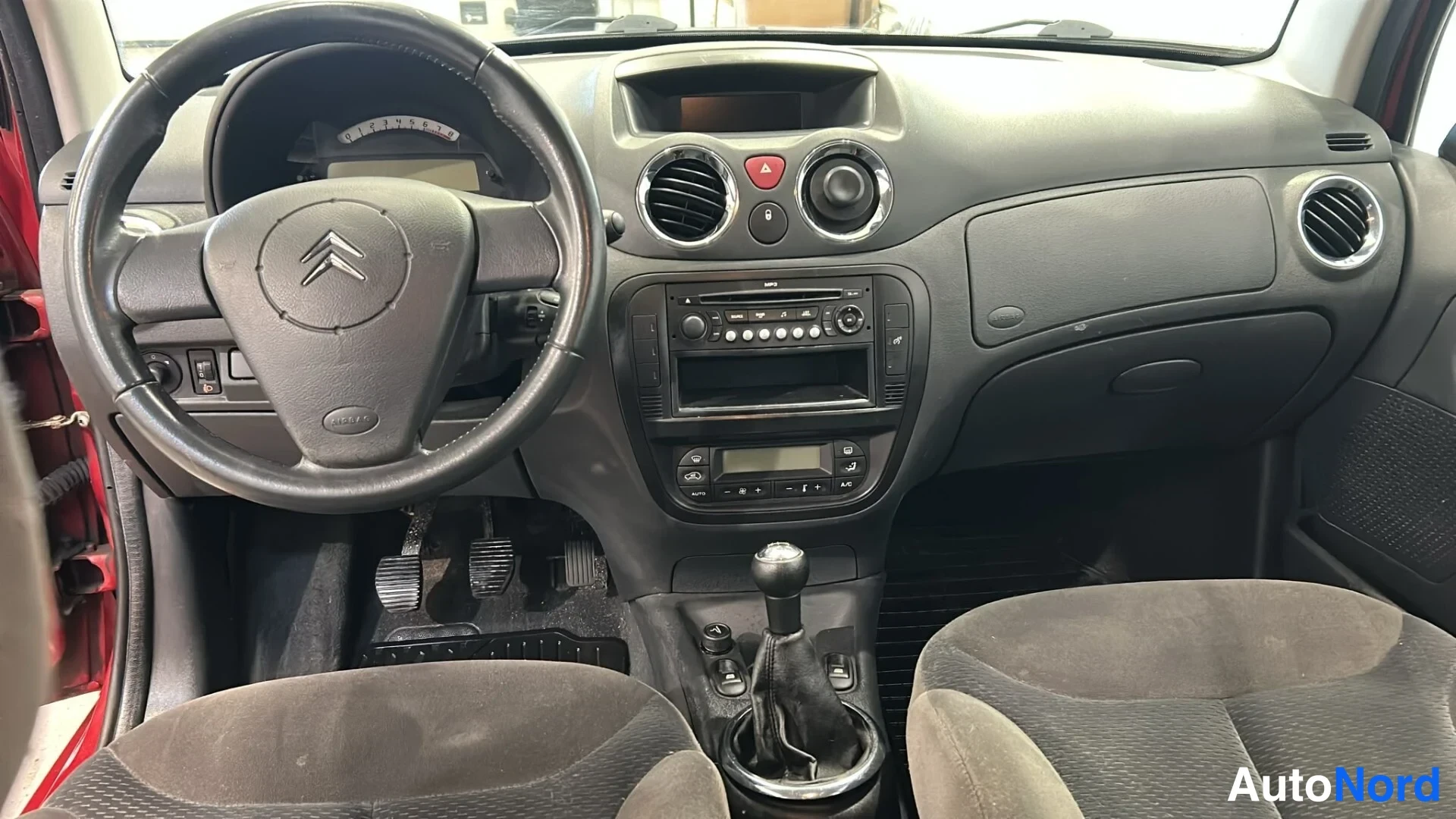 Muu: Citroenin ohjaamo etuosalta: ratti, manuaalivaihteiston vaihdekeppi, polkimet ja radio-konsoli näkyvät.