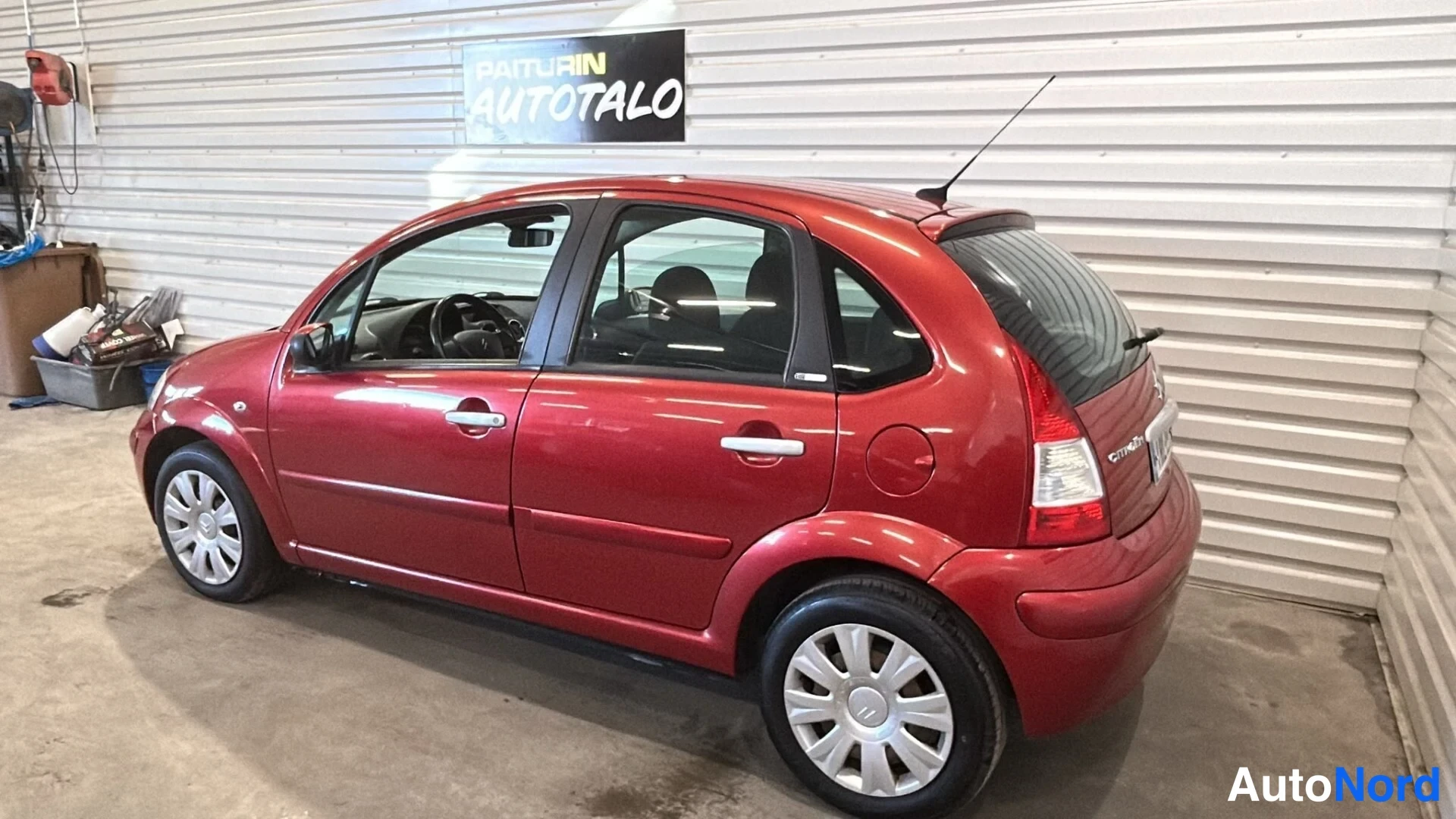 Takaviisto: Takaa ja vasemmalta kuvattu punainen hatchback sisätiloissa