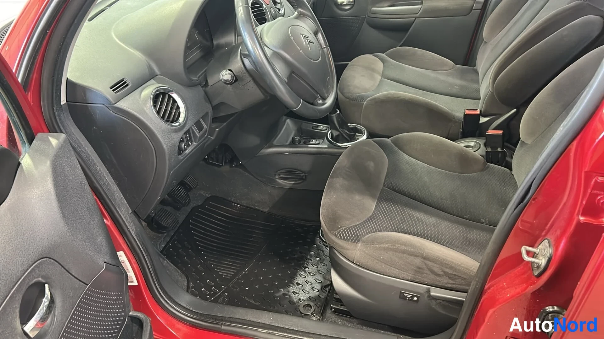 Muu: Citroenin etusetit ja kuljettajan lattia-matto kirkkaassa sisätilakuvassa, ovista paljastuu punainen koria.