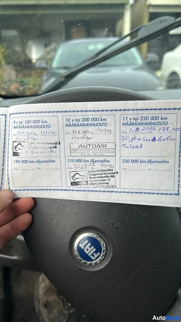 Muu: Huoltokirjan sivu Fiat-ohjauspyörän edessä: huoltomerkinnät 9–11 vuodelle, Autoasi- ja Laakkonen-leimoja, käsialamerkintöjä.