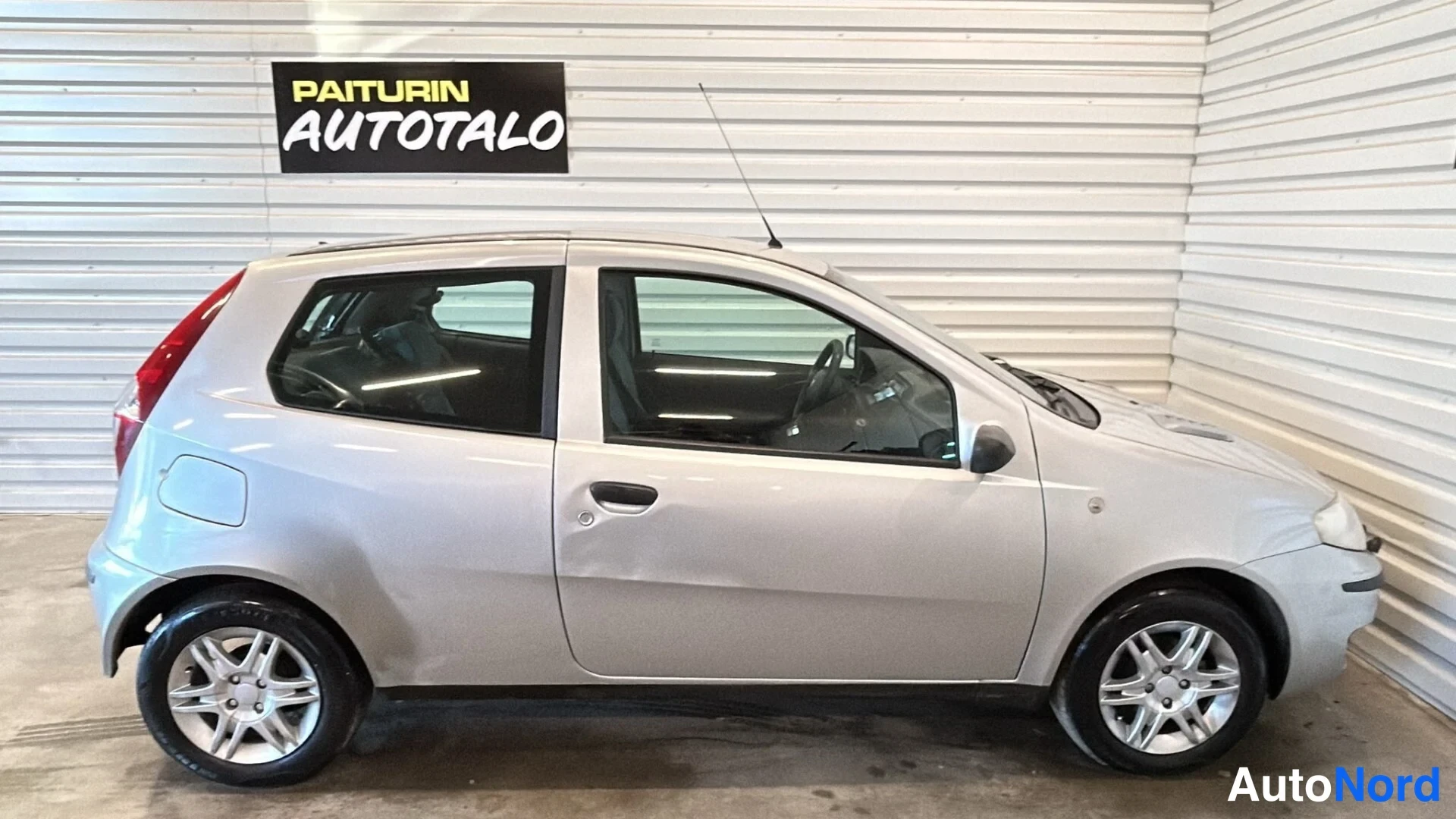 Etuviisto, nokka oikealle: Fiat Punto sivuprofiilista oikealta valokuvattuna hallissa, hopea koriväri, kaksiovinen farmarimallin kaltainen viistoperä.