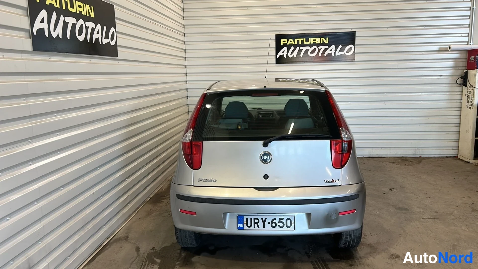 Takaa: Hopeanharmaa Fiat Punto suoraan takaa, Fiat-merkki ja Punto-teksti kannessa, rekisterikilpi.